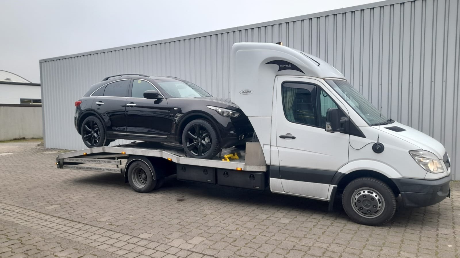 Chargement d’une voiture sur un camion porte-voitures chez le vendeur, état des lieux avant transport vers la France